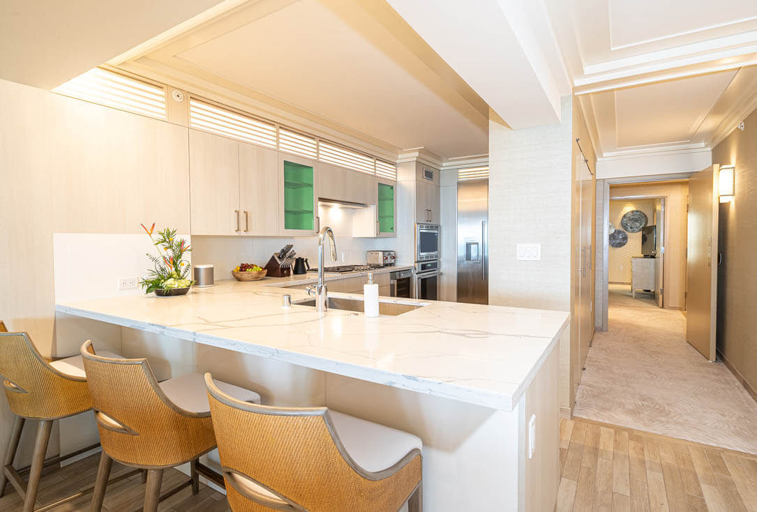 Kitchen with counter top seating, sink, stove, oven, refrigerator.