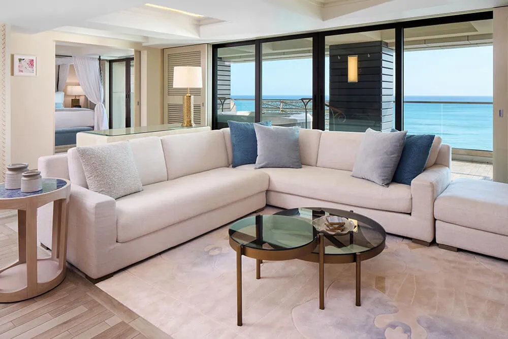 Living room with a sectional couch, coffee table, and balcony with ocean view.